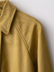 Close-up of mustard yellow suede bomber jacket collar showing premium stitching detail