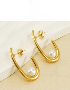 Détail de boucles d'oreilles en acier titane doré en U avec perles sur présentoir