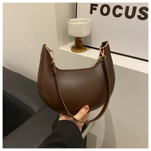 Close-up of a dark brown crescent underarm bag in smooth PU leather with gold hardware details