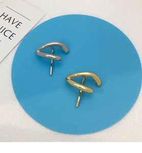 Close-up of twisted geometric metal stud earrings in gold and silver finishes