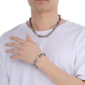 Silver coffee bean link chain set for men worn on neck and wrist over white t-shirt