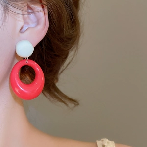 Détail de boucles d'oreilles ovales en résine rouge et blanche sur un mannequin