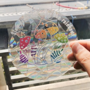 Holographic mushroom window decal reflecting rainbow light on a circular glass sticker