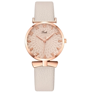 Macro shot of rose gold watch face with textured relief pattern and bowknot detail