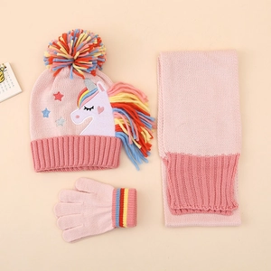 Détail d'un ensemble d'hiver rose avec patch licorne et pompons colorés sur le bonnet