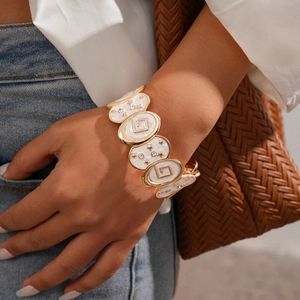 Close-up of vintage gold elastic bracelet with white enamel stars on a model's wrist