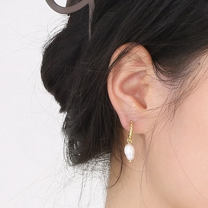 Baroque twist gold hoop earrings with irregular white pearl pendants on model