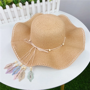 Detail of summer straw hat with wooden beads and colorful lace leaf pendants