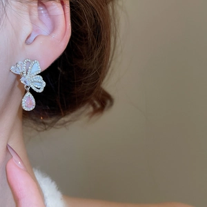 Close-up of silver butterfly drop earring with a pink teardrop gemstone and white zircon