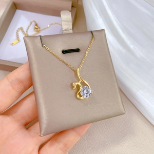 Elegant gold-plated swan pendant necklace with a large clear zircon on a beige display