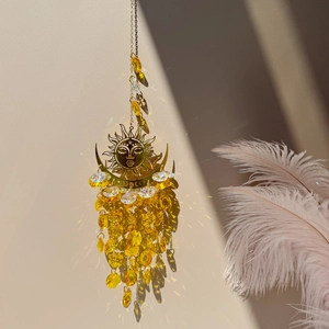 Golden sun crystal suncatcher reflecting sparkling light shadows on a beige wall background