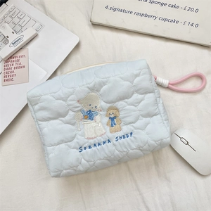 Detail of light blue quilted makeup bag with cute sheep embroidery and pink zipper