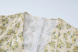 Détail d'une robe fleurie jaune avec feuilles vertes et fermeture éclair blanche invisible