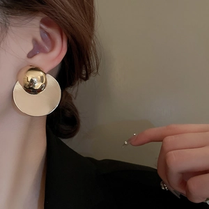 Detailed view of large gold geometric layered disc earrings worn by a model