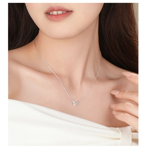 Close-up of a silver butterfly pendant necklace with zircons on a model's collarbone