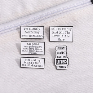 5-piece set of black and white enamel pins with humorous quotes on a white canvas bag