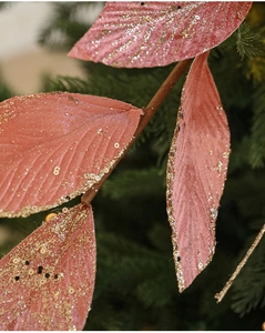 Macro detail of pink velvet Christmas leaf with golden glitter and fabric texture