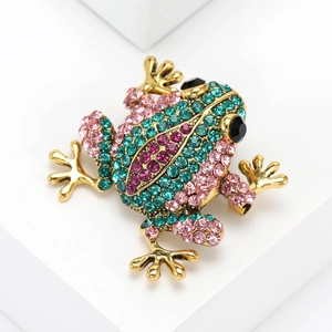 Charming green and pink rhinestone frog brooch with golden base on white pedestal