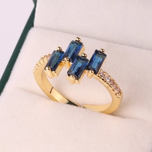 Detail of gold plated ring with blue rectangular zircons and white side stones