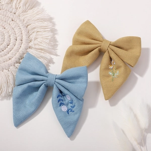 Détail de pinces noeuds en lin bleu et jaune avec broderies florales délicates