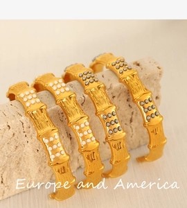 Detail view of golden bamboo pattern cuff bracelets with inlaid grey and white pearls