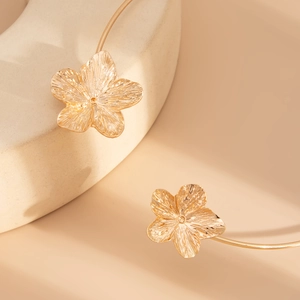 Detail of gold metal choker featuring two intricately textured five-petal floral charms