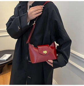 Close-up of bright red patent leather shoulder bag with elegant gold metal lock clasp