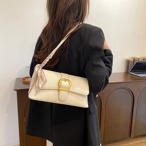 Cream shoulder bag with litchi texture leather and silk scarf detail on a model