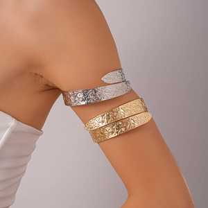 Close-up of vintage embossed metal arm cuffs with floral patterns in gold and silver