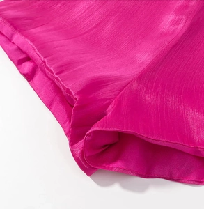 Detail of rose red pleated fabric texture and stitching on the irregular dress hemline