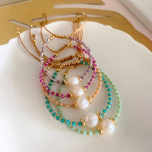 Close-up of assorted colorful beaded pearl bracelets in a white ceramic dish