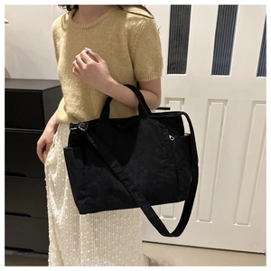 Detail of black corduroy tote bag showing side pocket and adjustable crossbody strap