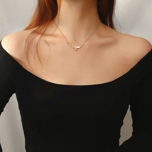 Elegant gold butterfly necklace with white shell pendant on a female model's collarbone
