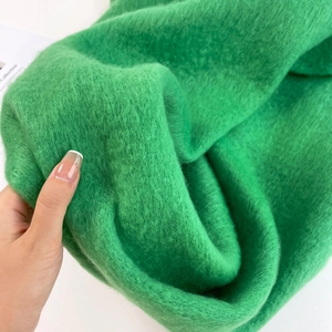 Close-up of soft green mohair fabric texture showing thick plush material and hand feel
