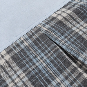 Détail du tissu bleu clair cousu avec une matière en coton et lin à carreaux bleu-gris