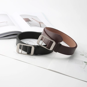 Minimalist leather belts in black and brown with matte metal buckles on a magazine