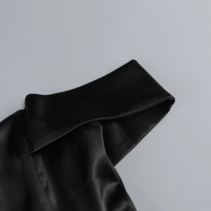 Détail de la robe en satin noir montrant la texture soyeuse de qualité et les coutures