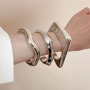 Macro shot of silver irregular geometric polished wide bangles with a mirror finish