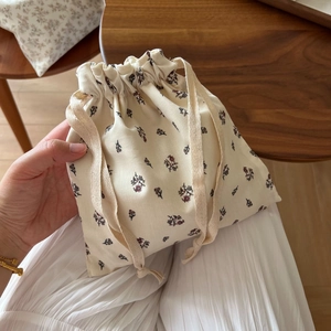 Detailed close-up of small floral drawstring bag in cotton held in hand at home