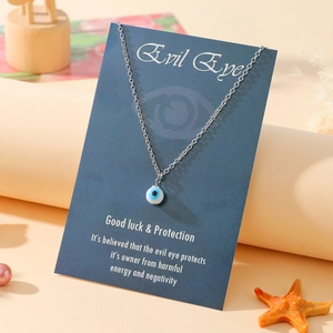 Detail of evil eye pendant necklace on a decorative gift card with beach accessories
