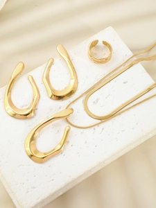Detailed view of gold jewelry set with thick ring and earrings on a white plaster stand