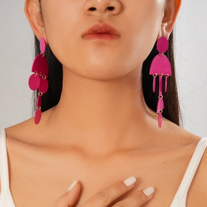 Dettaglio di orecchini a nappa magenta con maglie circolari geometriche su una modella