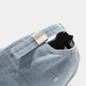 Detailed macro view of the adjustable silver metal buckle on a light blue denim baseball cap