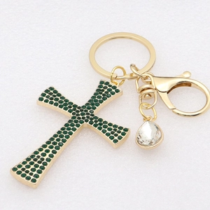 Macro shot of gold cross keychain with green rhinestones and a clear teardrop crystal charm
