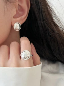 Close-up of silver hammered texture earrings and matching ring set worn by a model