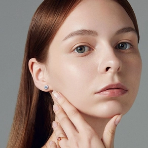 Detail of classic silver round-cut zircon stud earrings on model with jewelry styling