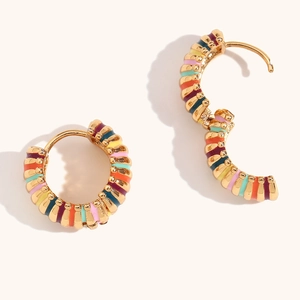 Detail of gold hoop earrings with multi-colored enamel stripes and hinged closure mechanism