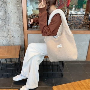 Detail view of a beige plush tote bag with soft texture shown in a lifestyle scene