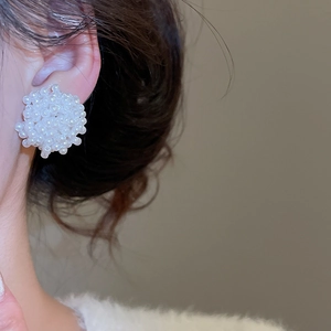 Détail de boucles d'oreilles clous en grappe de perles blanches portées par un mannequin