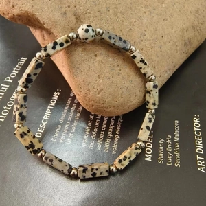 Detailed view of spotted stone beads with metallic spacers on a rustic rock display